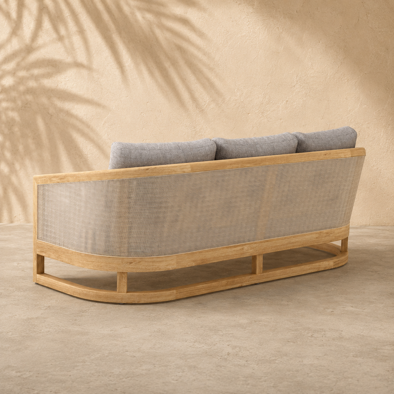 Wooden outdoor sofa with gray cushions against a beige wall with leaf shadows