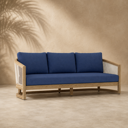 Blue cushioned sofa with wooden frame against a beige wall