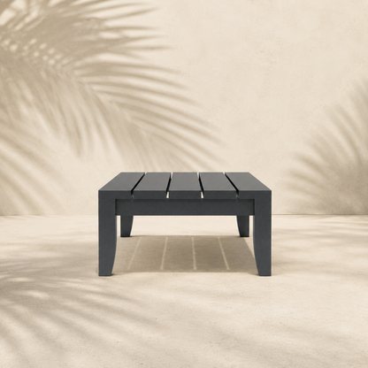 Black rectangular table on a sandy surface with a blurred natural background