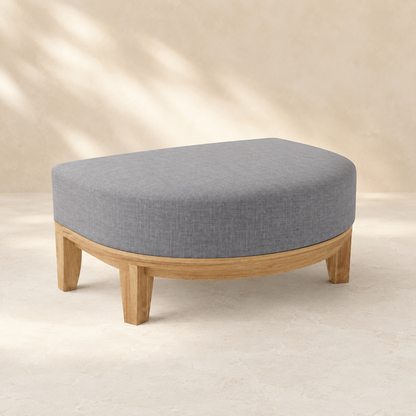 Oval ottoman with gray cushion and wooden legs on a beige background