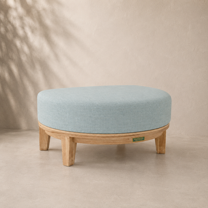 Round ottoman with light blue cushion and wooden legs on a beige background