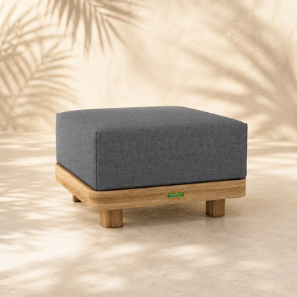 Gray cushioned ottoman with wooden legs on a neutral background